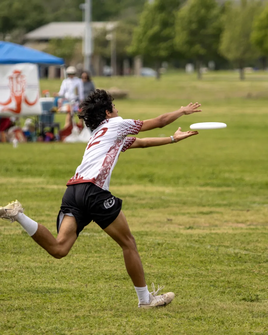 An ultimate frisbee player stretching at full extension to catch a disc