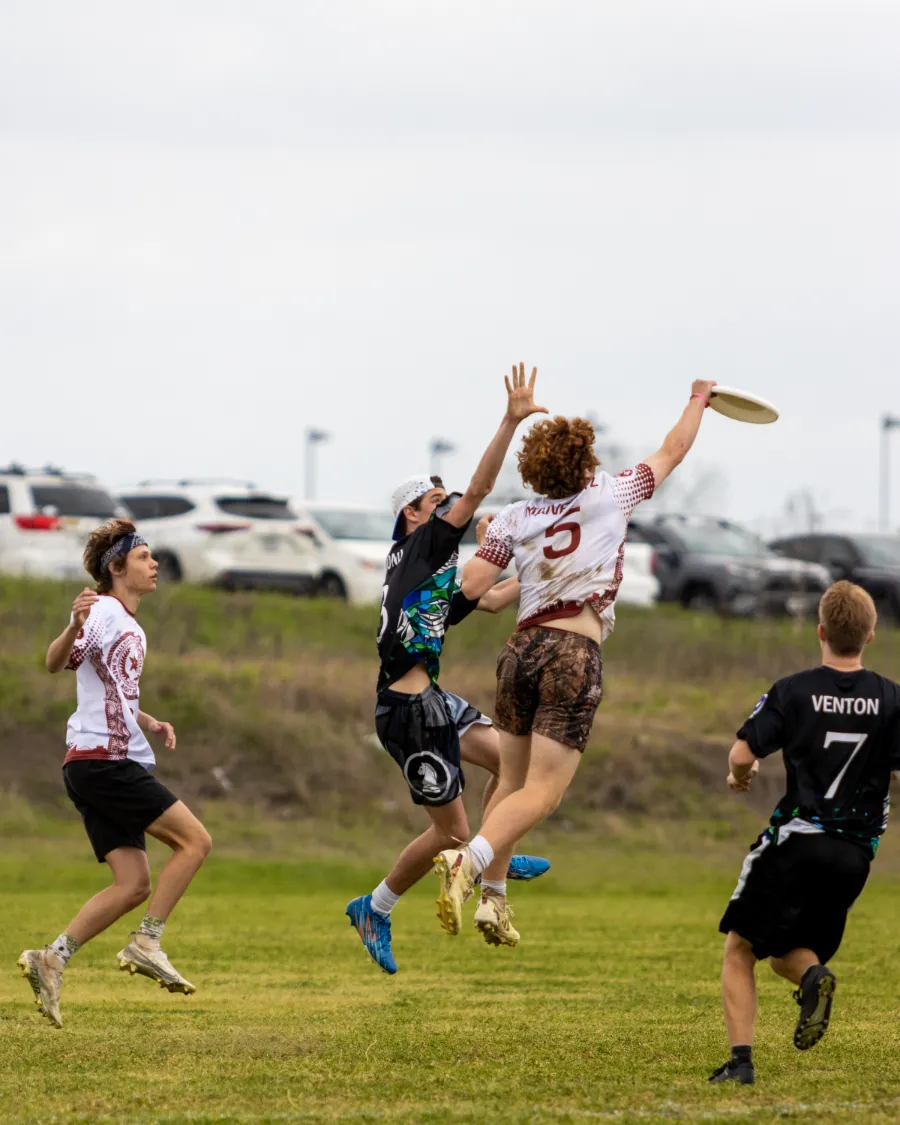 Ultimate frisbee players jumping together to contest a disc high in the air