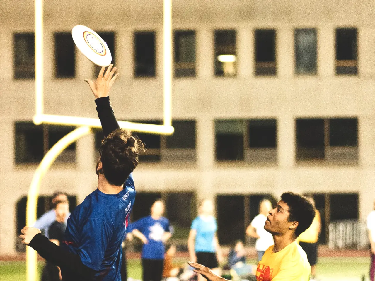 Two ultimate frisbee players contesting a disc in the air during a point on a marked field